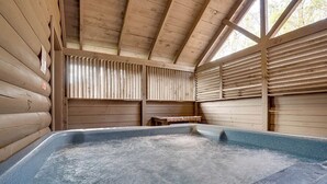 Uma banheira de hidromassagem em uma cabana de madeira com paredes e teto inclinados.