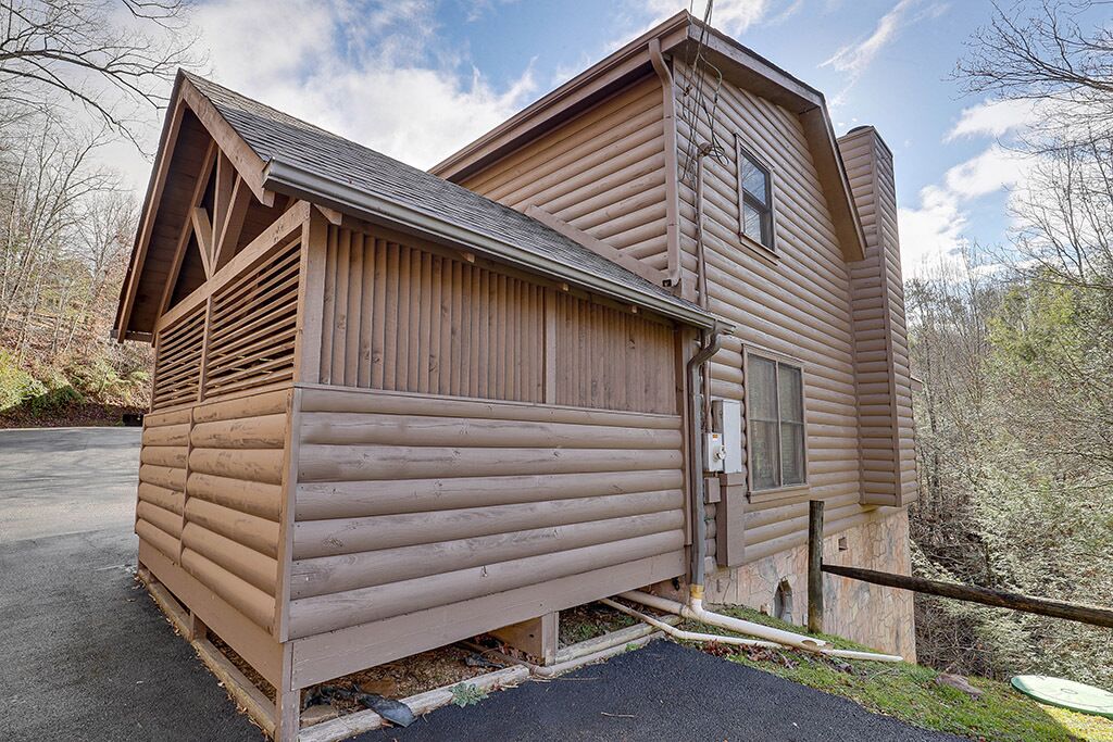 A log cabin with a sloped roof, a front porch, and a window.