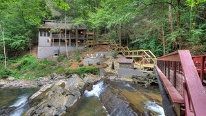 Un chalet rustique doté d’une terrasse en bois et situé près d’une cascade.