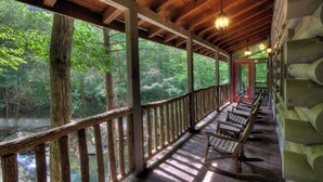 Une terrasse en bois, dotée de bancs, qui offre une vue sur une zone boisée et une rivière.