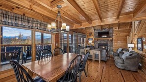 Un intérieur en bois comprenant une table à manger, des chaises, une cheminée et un téléviseur.