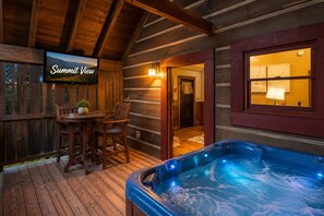 A wooden cabin interior with a hot tub, a dining area with chairs and a table, and a television displaying 'Summit View'. - Sevierville - Summit View - 1 Bdrms. (Sevierville)