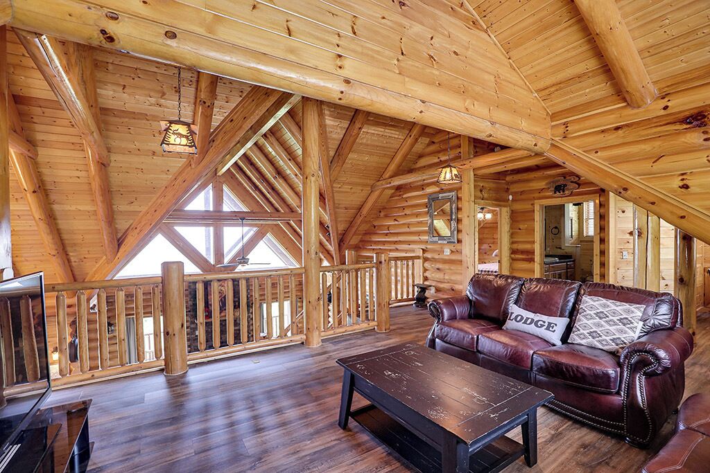 A spacious loft with wooden beams, a leather sofa, and a wooden coffee table.