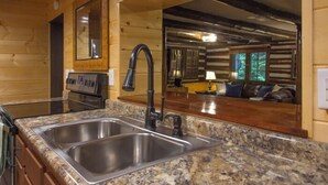 Una cocina con encimeras de granito, fregaderos de acero inoxidable y paredes de madera.