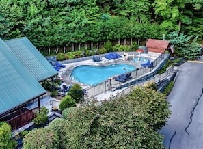 A swimming pool with a surrounding deck, a covered seating area, and a view of a forested area. - Adorable Cabin w/ Hot Tub & Views (Gatlinburg)