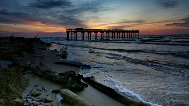 Un molo che si protende nell'oceano al tramonto.