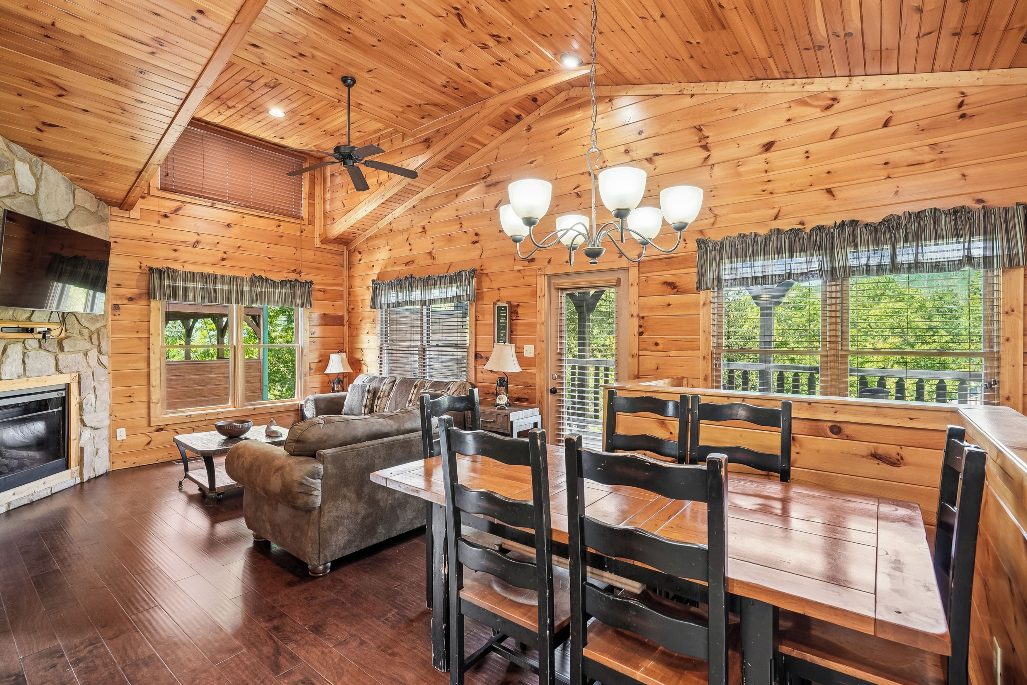A wooden interior with a dining table, chairs, a sofa, and a fireplace.