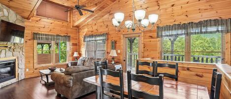 A wooden interior with a dining table, chairs, a sofa, and a fireplace.
