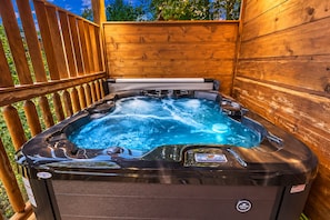 Un bain à remous doté d’un panneau de commande, entouré d’une terrasse et de murs en bois.