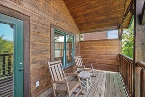 Una cabaña de madera con porche, dos sillas y una mesa.