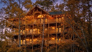 A multi-story log cabin with balconies, surrounded by trees. - Expansive Luxury Cabin w/ Games, Theater & Views (Gatlinburg)