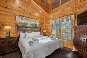 A wooden-paneled room with a bed, a dresser, and a television. - Modern Mountain Getaway w/ Hot Tub & Arcade (Gatlinburg)