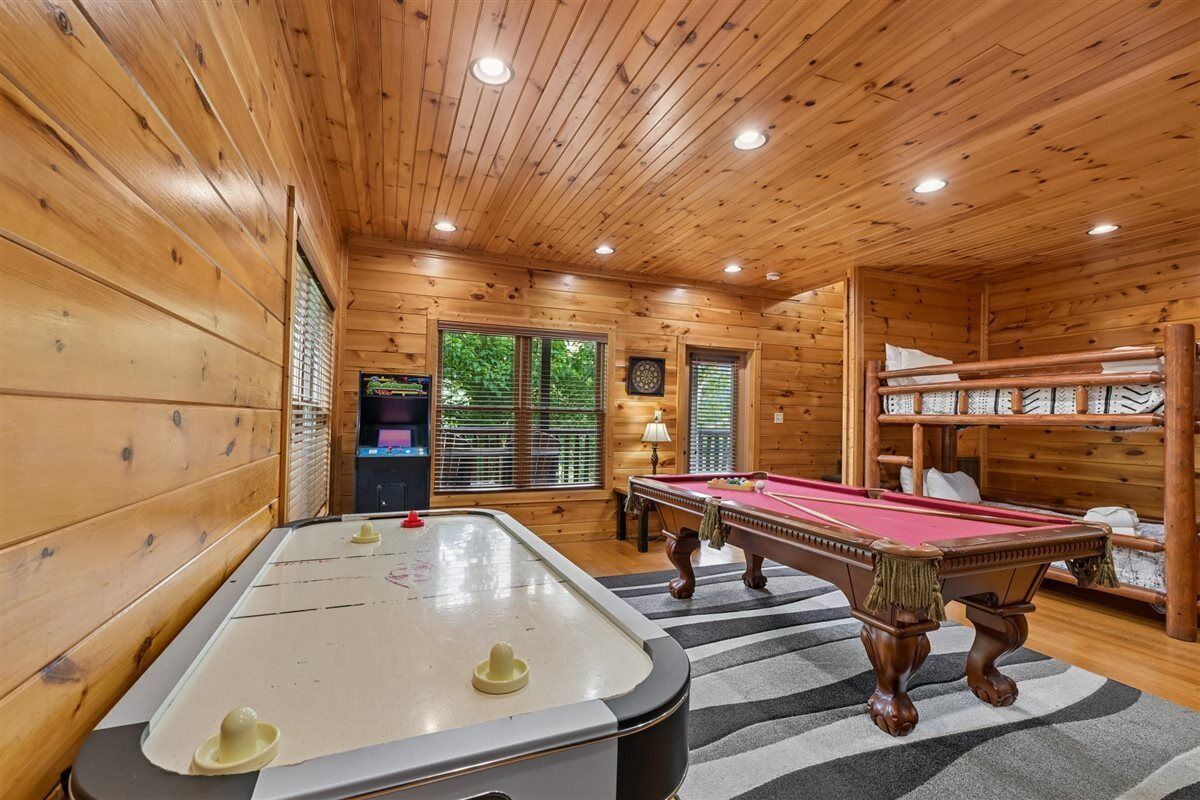 Une table de billard dans une pièce en bois, avec un plafond et des fenêtres.