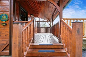 A wooden porch with a wooden staircase leading to a covered area.