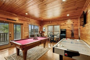 Een houten chalet met een pooltafel, een tafelvoetbaltafel en een eethoek.