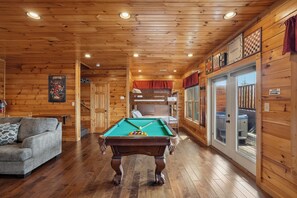 Una habitación acogedora con mesa de billar, sofá y sala de juegos con diversos juegos de mesa.