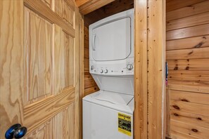 Ein kleiner Waschraum mit Waschmaschine und Trockner, Holzwänden und einer Tür mit Griff.