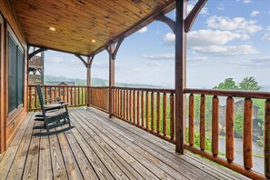 Une terrasse en bois avec une rambarde, un banc et une vue sur un quartier résidentiel.
