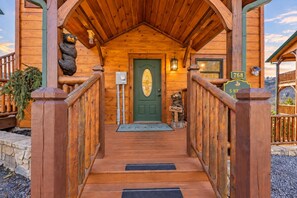 Une cabane en bois avec une porte verte, un escalier en bois et une pancarte sur laquelle on peut lire « Salut ».