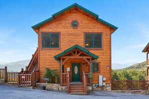 A wooden cabin with a green roof, a front porch, and a view sign.