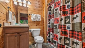 Un baño de cabaña de madera con inodoro, lavabo y toallero.