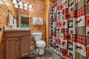 Un baño de cabaña de madera con inodoro, lavabo y toallero.