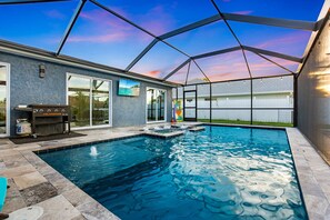 A swimming pool with a covered patio area, a barbecue grill, and a view of the backyard. - Pool, Spa & Dock Modern Canal-Front Escape (Cape Coral)