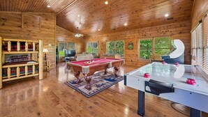 A spacious room with wooden walls and ceiling, a pool table, a foosball table, and a sofa. - Relaxing Smoky Mtn. Getaway w/Views & Family Fun! (Gatlinburg)