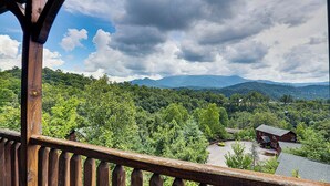 A wooden balcony railing overlooking a lush green landscape with a mountain range in the distance. - Relaxing Smoky Mtn. Getaway w/Views & Family Fun! (Gatlinburg)