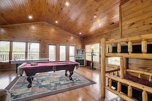 Un intérieur en bois comprenant une table de billard, un porte-billes et un support à queues de billard.