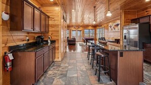 A wooden cabin interior with a kitchen, bar area, and a fireplace.