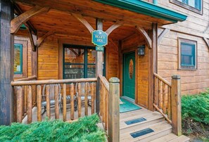 A wooden cabin with a porch, a green door, and a sign reading 'Bear's Den.'
