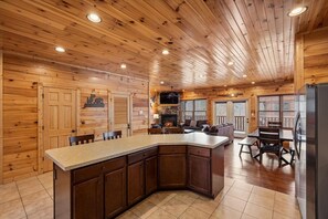 A log cabin interior with a kitchen island, dining area, and a fireplace.