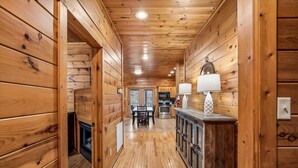 Ein Holzblockhaus-Interieur mit Holzboden, Kamin, Essbereich und Küche inklusive Mikrowelle.