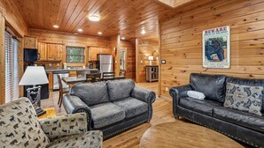 Ein Holzblockhaus-Interieur mit einer Küche, zwei Sofas und einem Warnschild an der Wand.