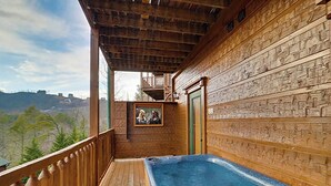 A wooden deck with a hot tub, wooden walls, and a framed picture. - Tranquil Rustic Cabin w/ Game Area & Hot Tub (Gatlinburg)