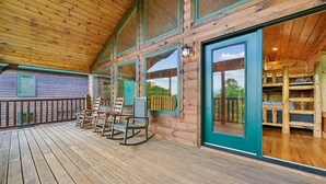 Um deck de madeira com cadeiras de balanço e vista para o exterior.