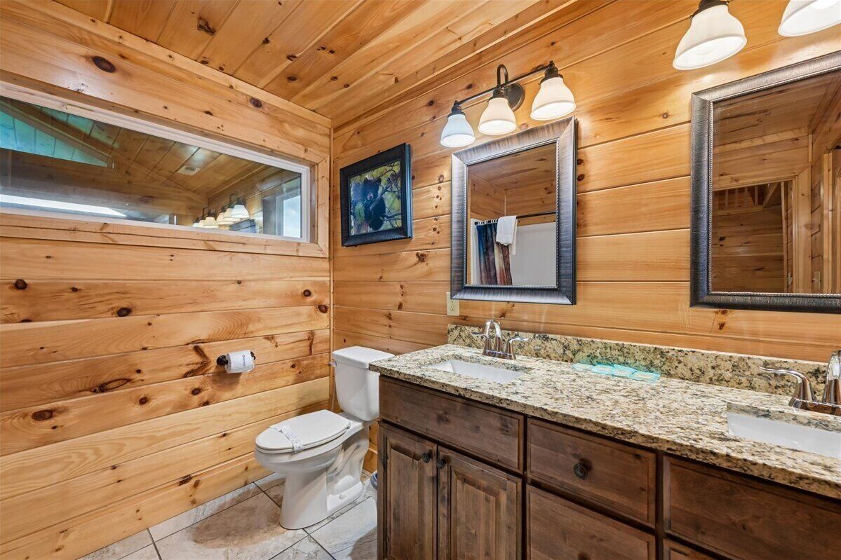 A wooden-paneled bathroom with a toilet, sink, and mirror.