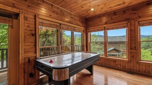 Une pièce au plancher de bois, équipée d’une table de billard, de grandes fenêtres et offrant une vue sur l’extérieur.