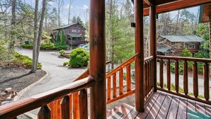 Une terrasse en bois avec une rambarde, une vue sur un chalet et un chemin menant à celui-ci.