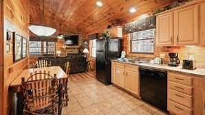 L'intérieur d'un chalet en bois comprend un coin repas, une cuisine et une cheminée.