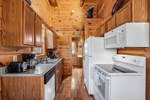 Una cucina compatta con mobili in legno, un forno a microonde, un frigorifero e una lavastoviglie.