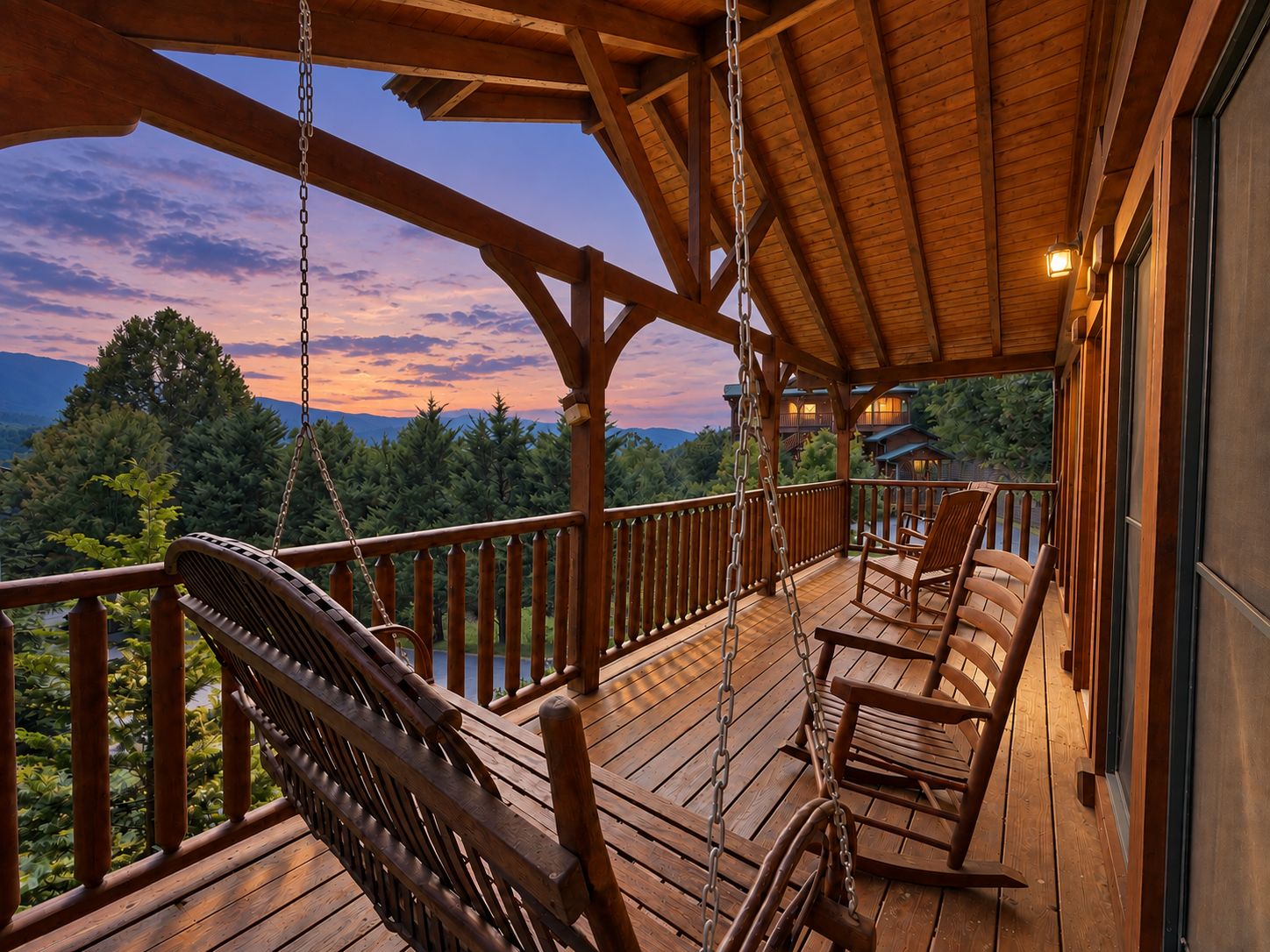 Une terrasse en bois avec un fauteuil suspendu et un fauteuil à bascule, offrant une vue sur un paysage boisé.