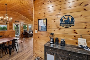 Een houten interieur met een eethoek, een koffiehoek en een bord waarop staat 'Welcome'.