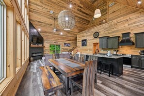 A wooden interior with a dining area, kitchen, and a fireplace. - Stylish Modern Mountain Haven w/ Hot Tub (Gatlinburg)