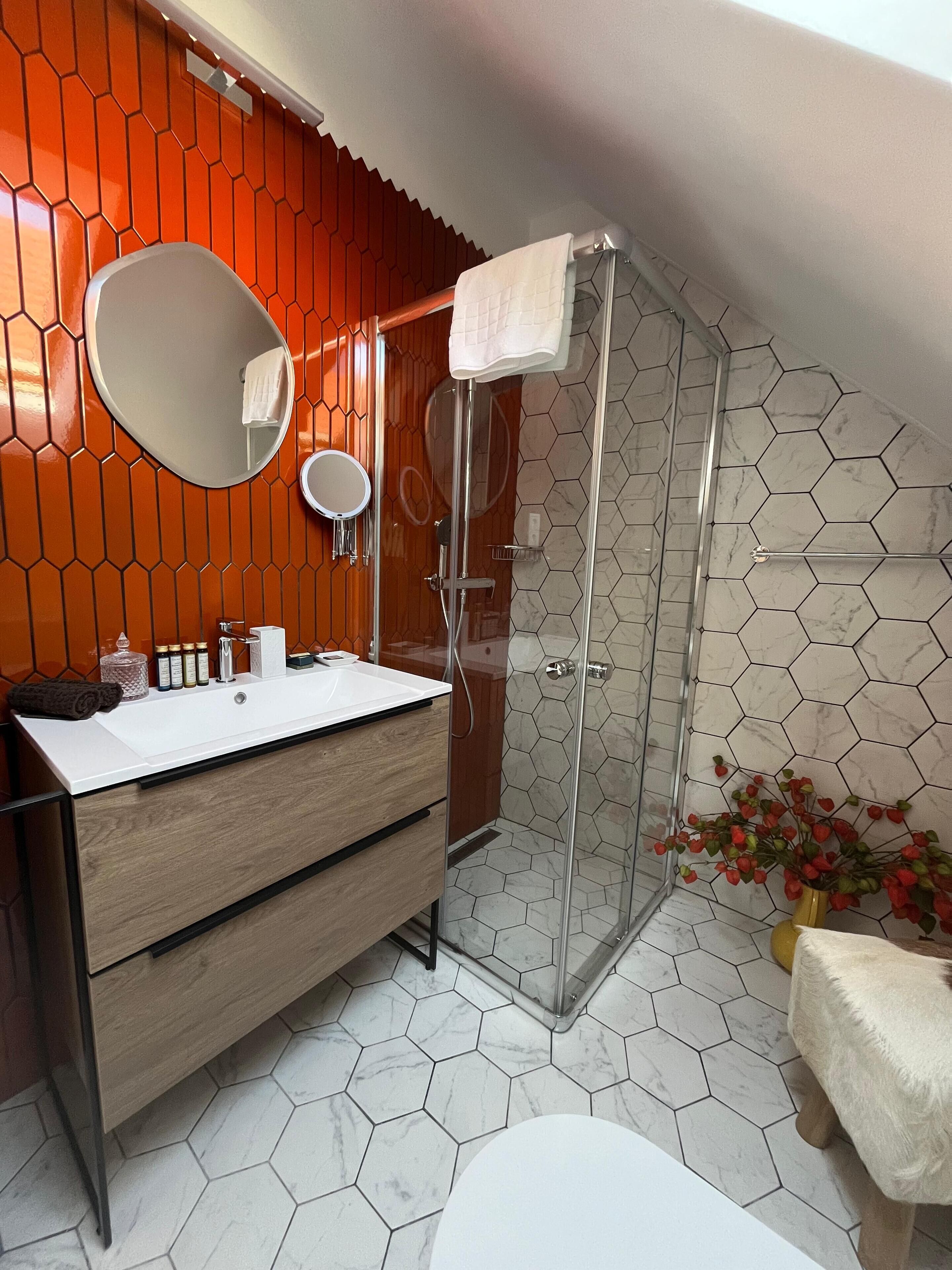 Ein modernes Badezimmer mit einem Holzwaschtisch, einer Duschkabine aus Glas und sechseckig gefliesten Wänden.