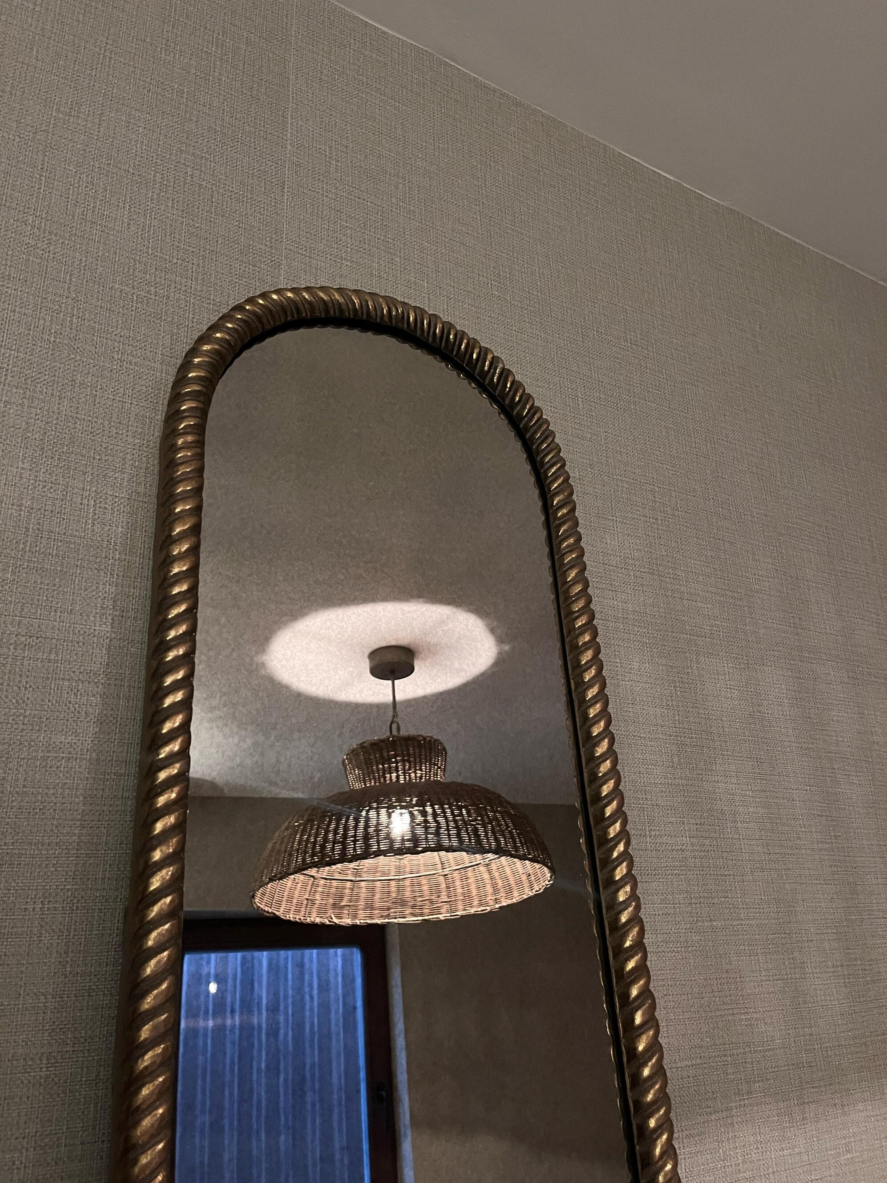 Un mirall amb marc daurat que reflecteix una lluminària penjada.