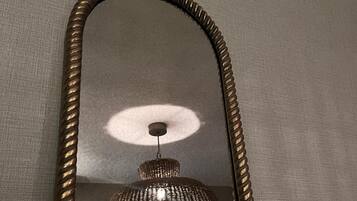 Un mirall amb marc daurat que reflecteix una lluminària penjada.