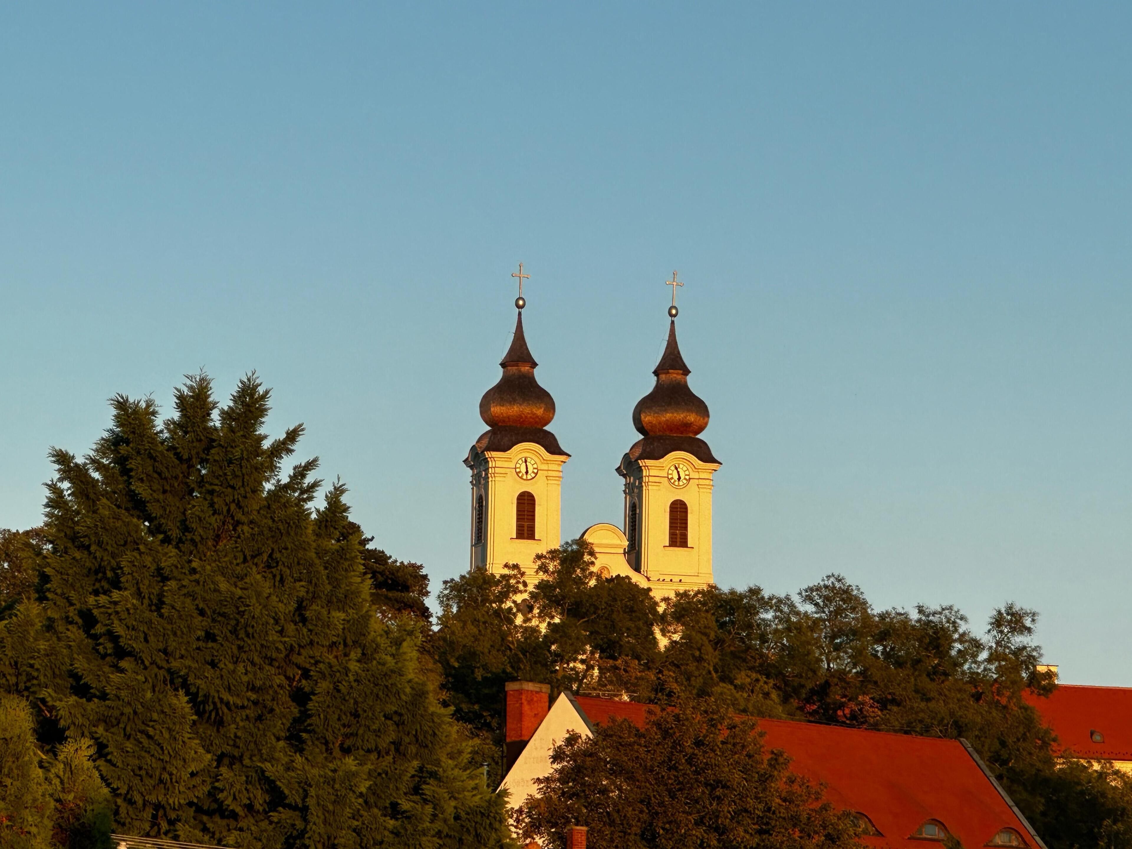 A church with two towers and a red-roofed building in the foreground.
