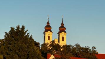 A church with two towers and a red-roofed building in the foreground.